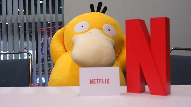 One photo shows a Psyduck plush sitting at a Netflix press conference table. 